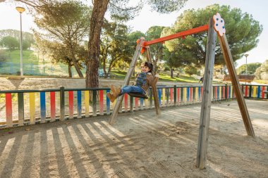Gülümseyen kız parkta salıncakta eğleniyor