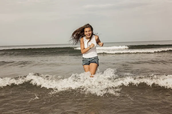 Adolescente feliz jugando con el agua en la orilla del mar del bea — Foto de Stock