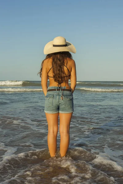 Mujer joven por detrás, con sombrero de verano y pantalones vaqueros en — Foto de Stock