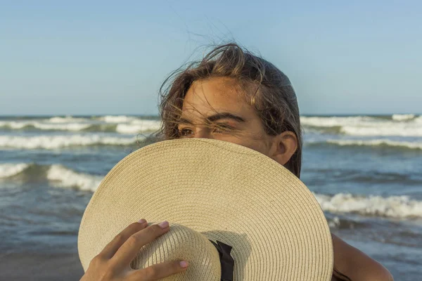 Chica y la playa se esconden en una playa sombrero de verano admirando la puesta de sol . — Foto de Stock