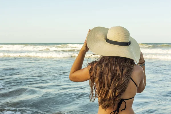Mujer joven por detrás, con sombrero de verano de playa mirando a la — Foto de Stock