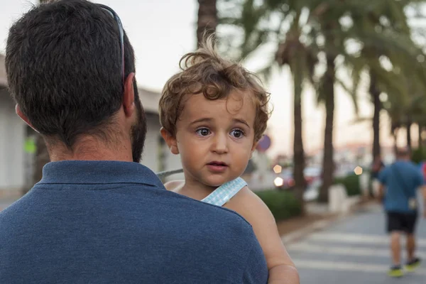 Erkek bir bebek tutan arka görünümü adam. Yaz plaj yer. 