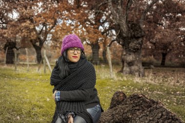 Orta çekim gözlük oturmak portre ciddi kadınla ağaç tr