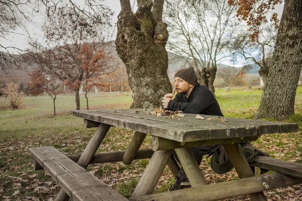Homem com chapéu de lã sentado no banco no parque no outono bac — Fotografia de Stock