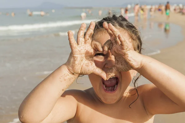 Ragazza che guarda attraverso un cuore disegnare con le mani. Spiaggia. Estate — Foto Stock