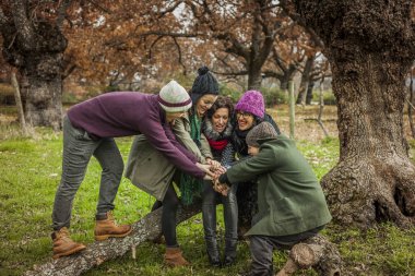 Grup portresi eller yığını yapıyor bir ağaç gövde üzerinde oturmak. A