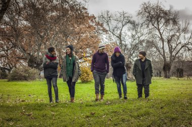 Sonbaharda park çevresinde yürürken konuşan arkadaşlar