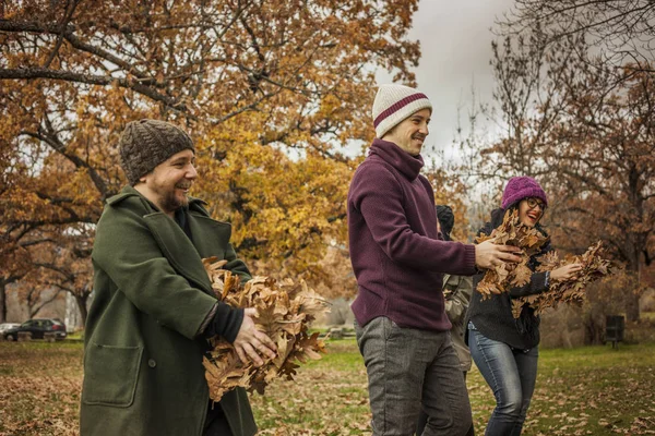 Arkadaşlar eğlenmeye yaprakları ile parkta. Sonbahar sahne