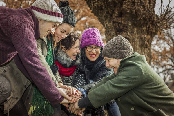 Teamwork playing and joining hands at the park. Autumn