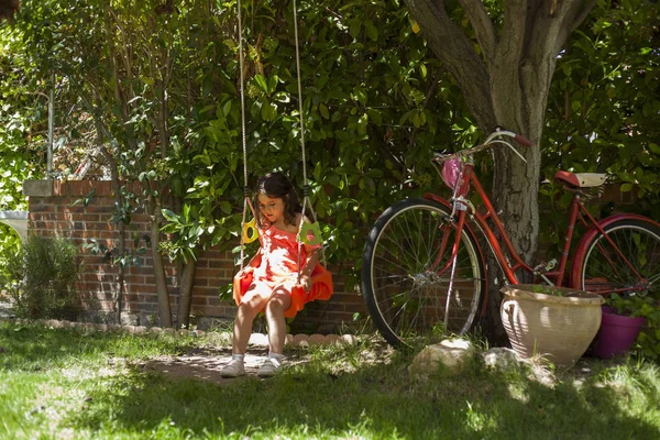 Chica balanceándose en el patio de recreo. Jardín. Naturaleza. Juegos — Foto de Stock