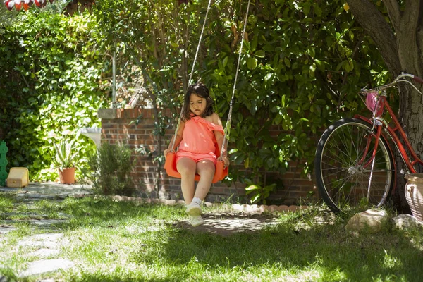 Girl swinging at the playground. Garden. Nature. Games