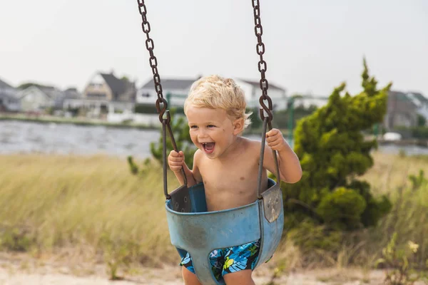 Menino feliz se divertindo no swing no playground. Hora de Verão — Fotografia de Stock
