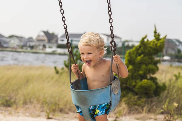 Buon bambino che si diverte sull'altalena al parco giochi. Ora legale — Foto Stock