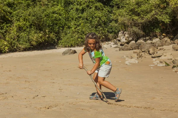 Ragazza che gioca con la sabbia in una spiaggia rocciosa. Spagna — Foto Stock