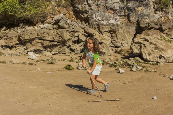 Ragazza che gioca con la sabbia in una spiaggia rocciosa. Spagna — Foto Stock