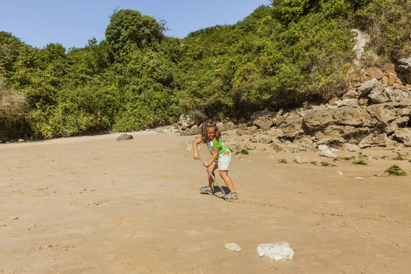 Ragazza che gioca con la sabbia in una spiaggia rocciosa. Spagna — Foto Stock