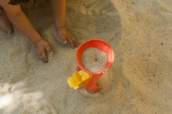 Mani gettare sabbia in un giocattolo mulino di plastica in una sabbiera. Spostamento — Foto Stock