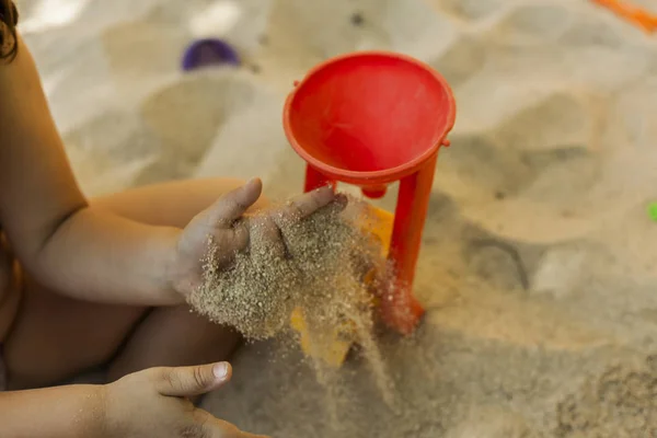 Mani gettare sabbia in un giocattolo mulino di plastica in una sabbiera. Spostamento — Foto Stock