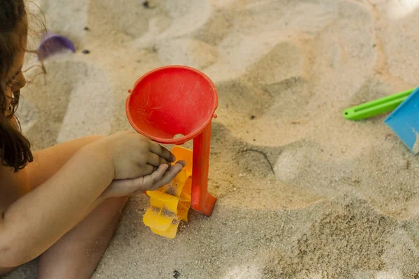 Mani gettare sabbia in un giocattolo mulino di plastica in una sabbiera. Spostamento — Foto Stock