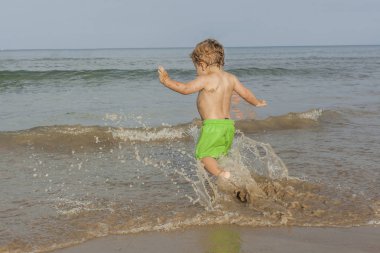 Splash plaj sahil içinde çalışan arka görünümü çocuk. Yaz Zamanı. 