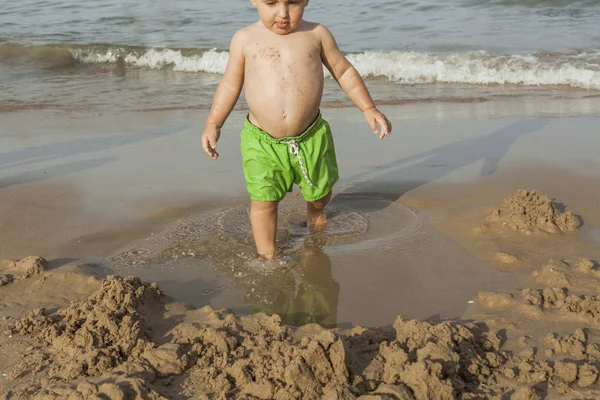 ビーチの海岸で遊ぶ水着を身に着けている男の子 — ストック写真