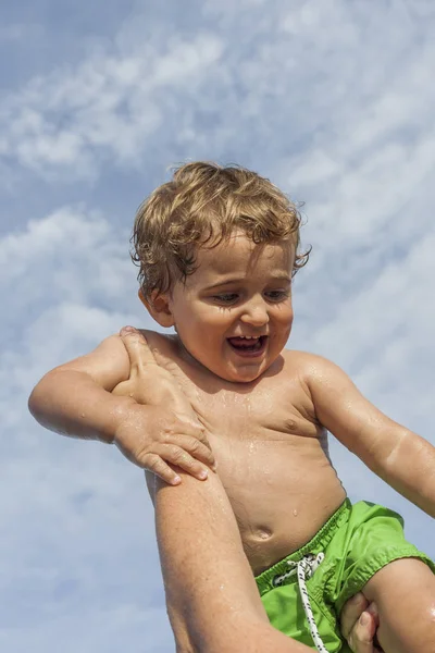 ビーチで男の子の赤ちゃんを笑顔を保持している母親 晴れた日の青空 家族の時間 — ストック写真