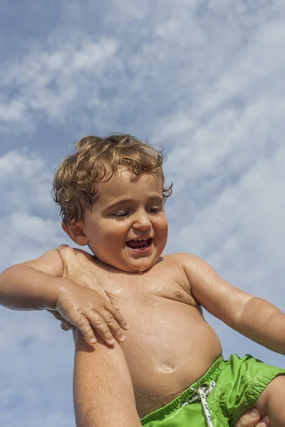 ビーチで笑顔の男の子の赤ちゃんをスローします 晴れた日の青空 家族の時間 — ストック写真