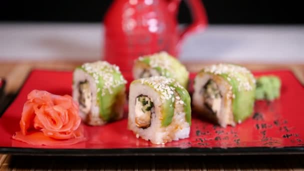 Японский зеленый суши на тарелке с палочками для еды на фоне бамбука — стоковое видео