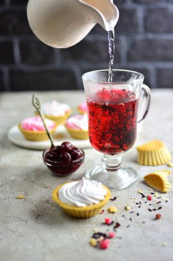 Bir bardak tatlı - tartlets ve kiraz reçeli bir masada kırmızı meyve çayı