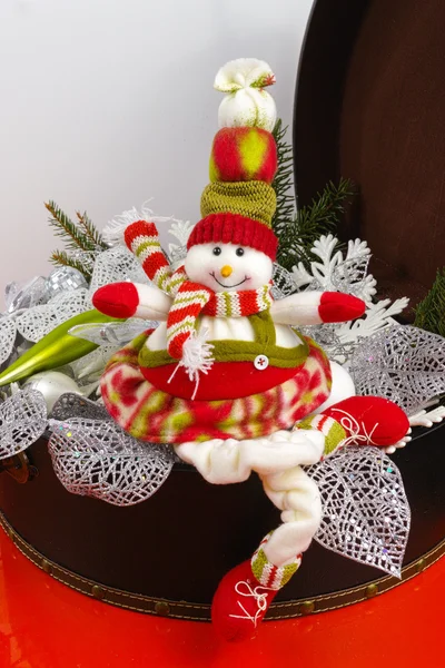 Funny snowman sits on vintage brorwn coffer with white christmas — Stock Photo, Image