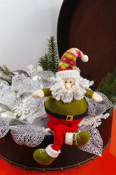 Santa Claus sits on vintage brown coffer with white christmas decoration — Stock Photo, Image