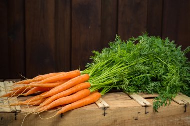 Ahşap kutu kopya alanı üzerinde taze turuncu havuç demet