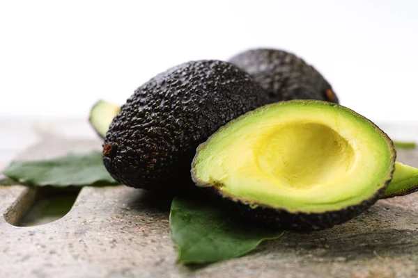 Green ripe avocado with leaves close up