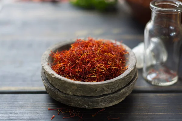 Raw Organic Red Saffron Spice in a clay bowl on wooden table