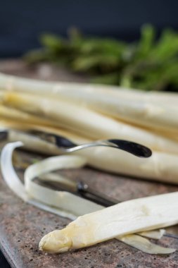 Bahar mevsimi - soyulmuş taze beyaz pişmemiş kuşkonmaz ve Soyucu