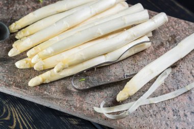 Bahar mevsimi - soyulmuş taze beyaz pişmemiş kuşkonmaz ve Soyucu