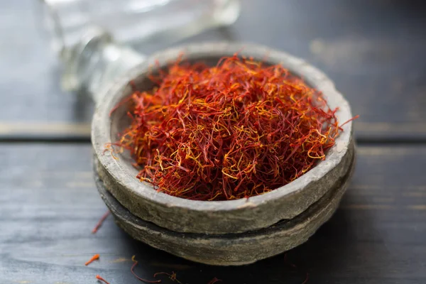 Especia de azafrán rojo orgánico crudo en un tazón de arcilla —  Fotos de Stock