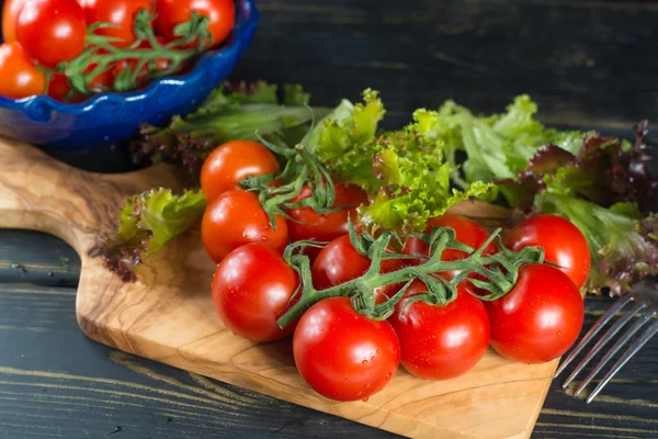 Fresh red small tomatoes and green leaf salad in blue bowl ready — Stock Photo, Image