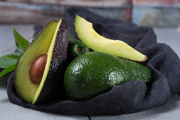 Grüne reife Avocado mit Blättern — Stockfoto