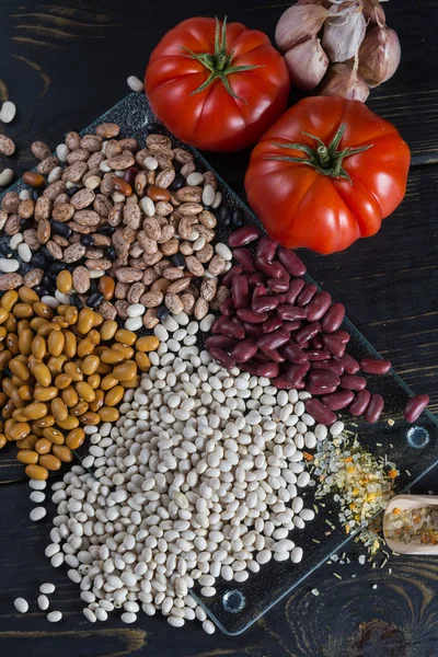 Assortment of beans on black wooden background. Soybean, red kidney bean, black bean,white bean, red bean and brown pinto beans