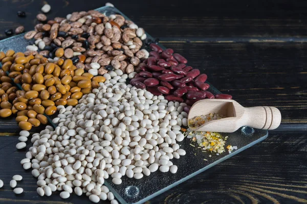 Assortment of beans on black wooden background. Soybean, red kidney bean, black bean,white bean, red bean and brown pinto beans