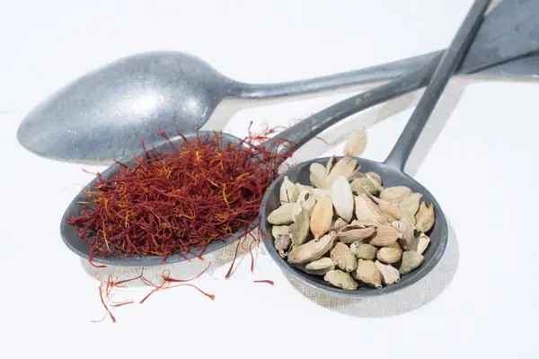 Raw Organic Red Saffron and Cardamom Spices in old tin spoons on