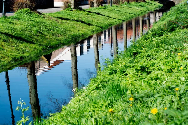 Spaziergang entlang des kleinen Kanals im alten holländischen Dorf, sonniger Sonntag Stockbild