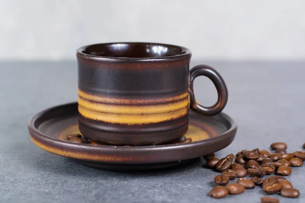 Кофейная чашка и кофейные зёрна на сером фоне — стоковое фото