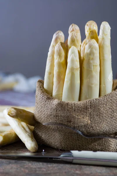 Frühlingszeit - frischer weißer Spargel im Klettenbeutel auf Granit — Stockfoto