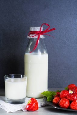 Taze inek sütü ve gri arka plan kopya alanı üzerinde olgun organik çilek