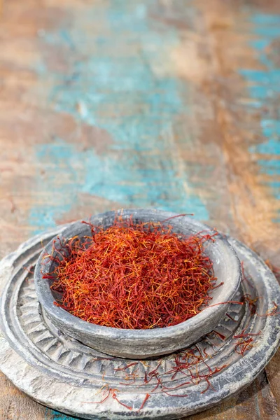 Dried organic red saffron Spice in a stone bowl on wooden backgr