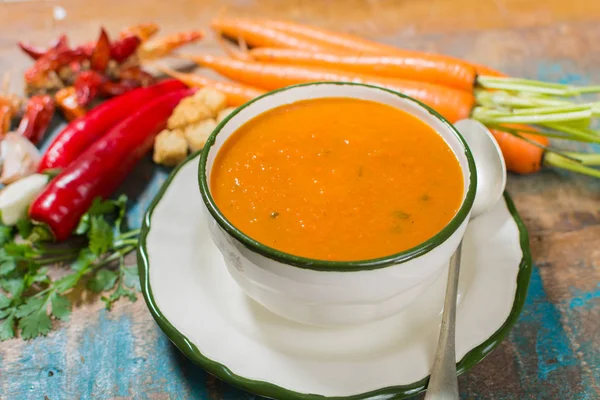 Harissa yapılmış sıcak biber, limon, sarımsak, mavi ahşap masa üzerinde kişniş ile baharatlı havuç çorbası