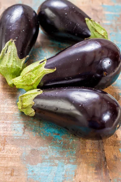 Ahşap arka plan üzerinde olgunlaşmış çiğ mor patlıcan