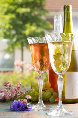 Soğuk Yaz şaraplar, beyaz ve gül, taze hava, açık çiçekler, güneşli gün, parti veya romantik kavramı ile yeşil bir bahçe içinde güzel bardaklarda servis